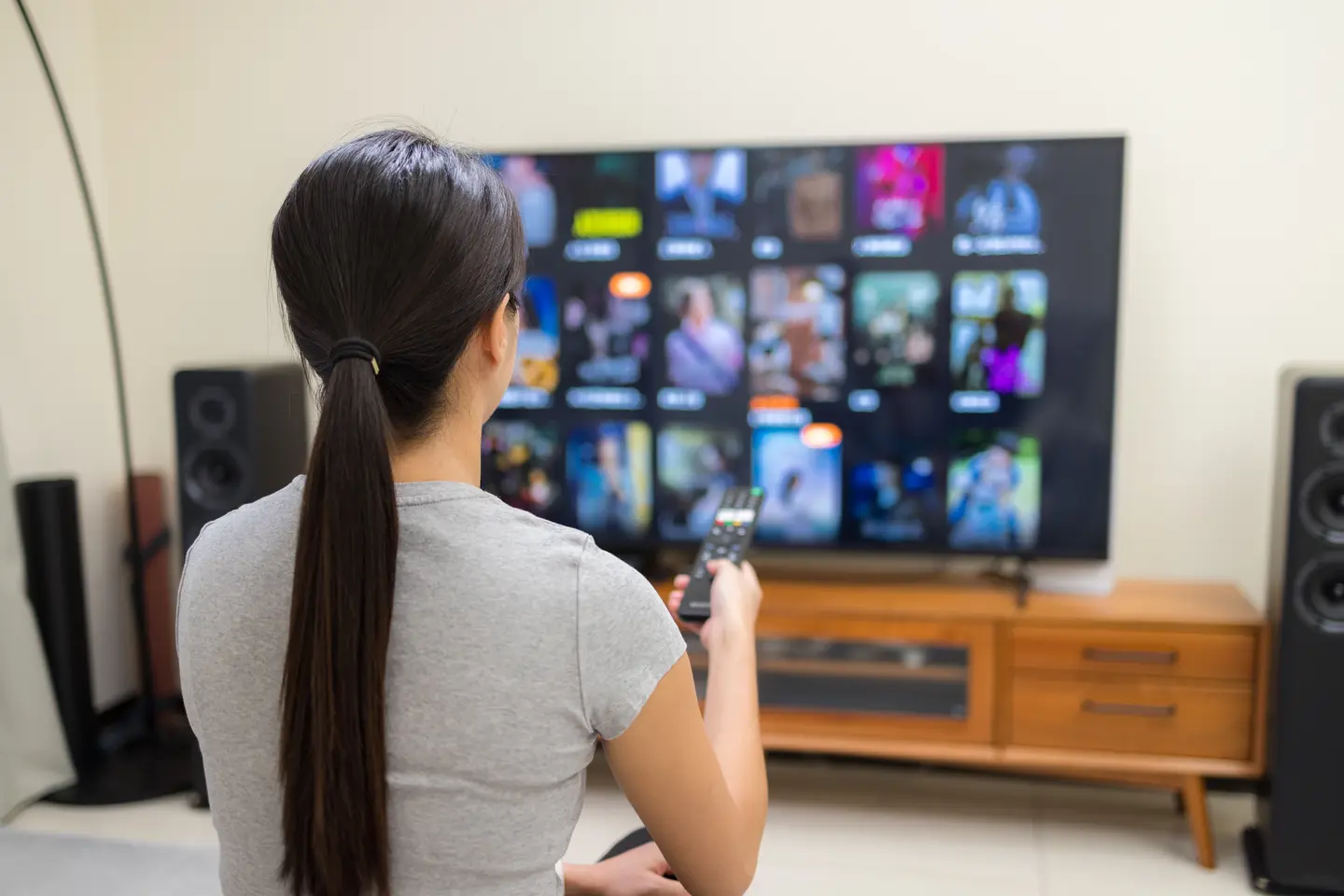 Woman choosing channels on Smart TV using IPTV Smarters 8k Pro subscription – best IPTV Smarters Player 2025.