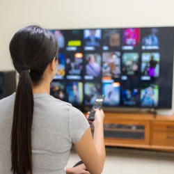 Watching IPTV Smarters Pro on Smart TV – IPTV Smarters Player & Subscription 2025. Woman choosing channels on Smart TV using IPTV Smarters 8k Pro subscription – best IPTV Smarters Player 2025.